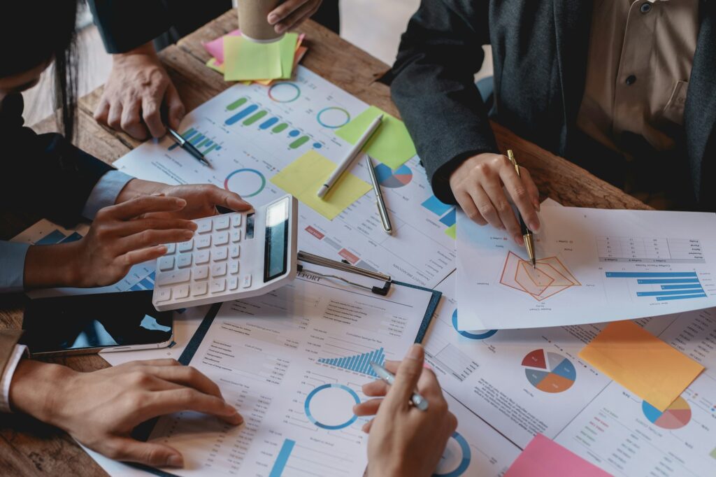 Business people in a meeting and using a calculator to calculate, plan, analyze, create graphs and c